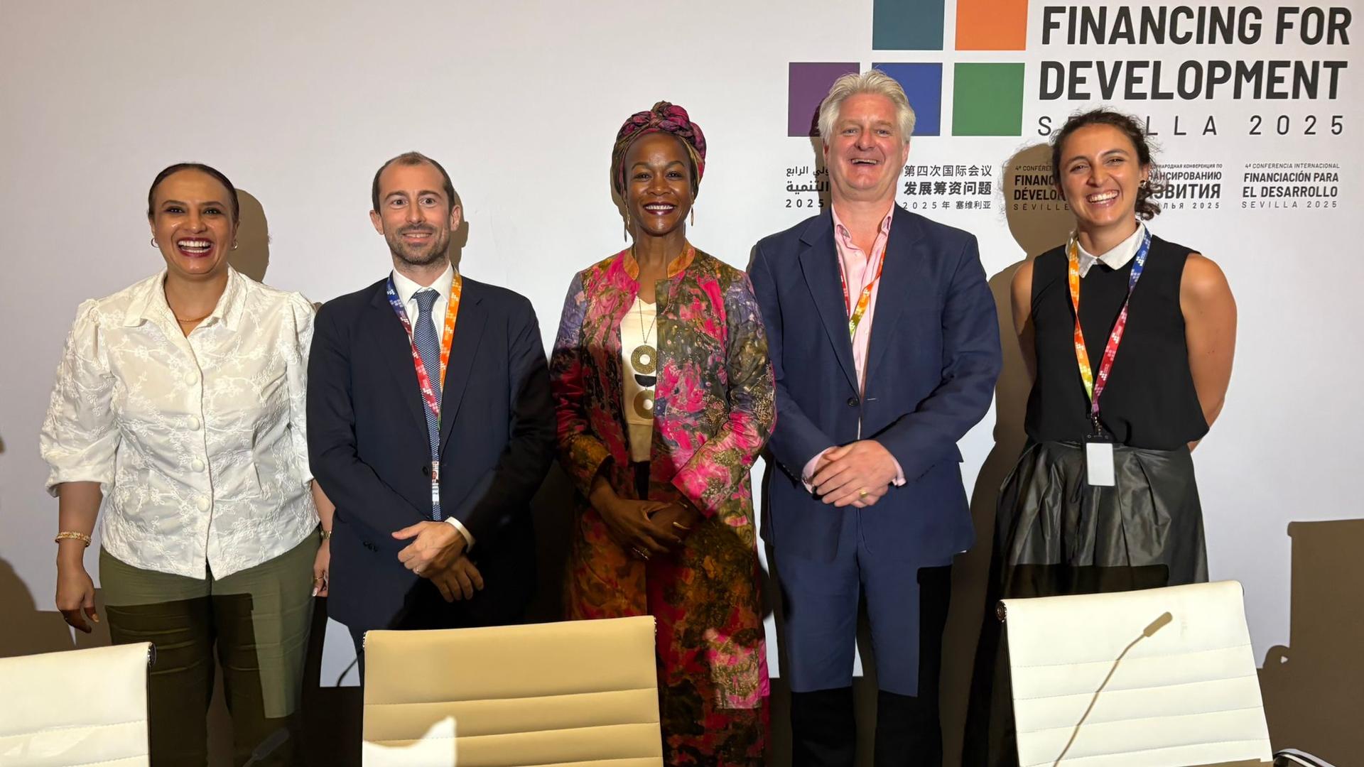 Six diverse professionals stand together at a financing-for-development event.