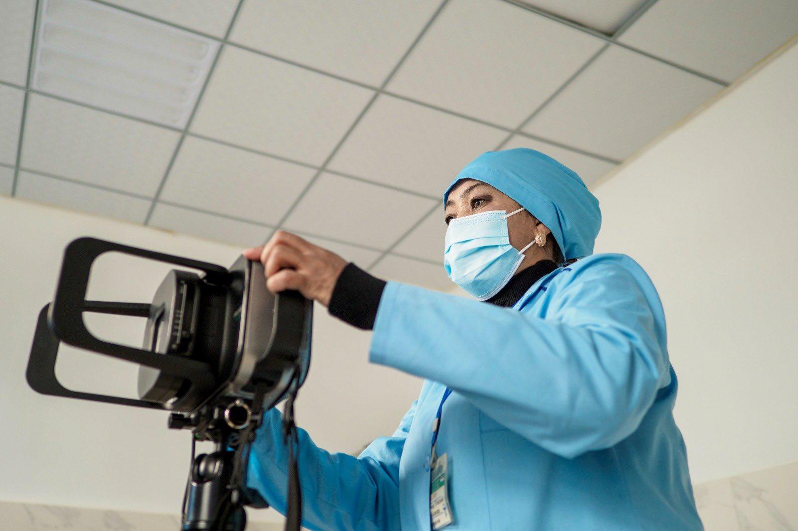 Surgeon in blue scrubs and mask adjusts a medical camera.