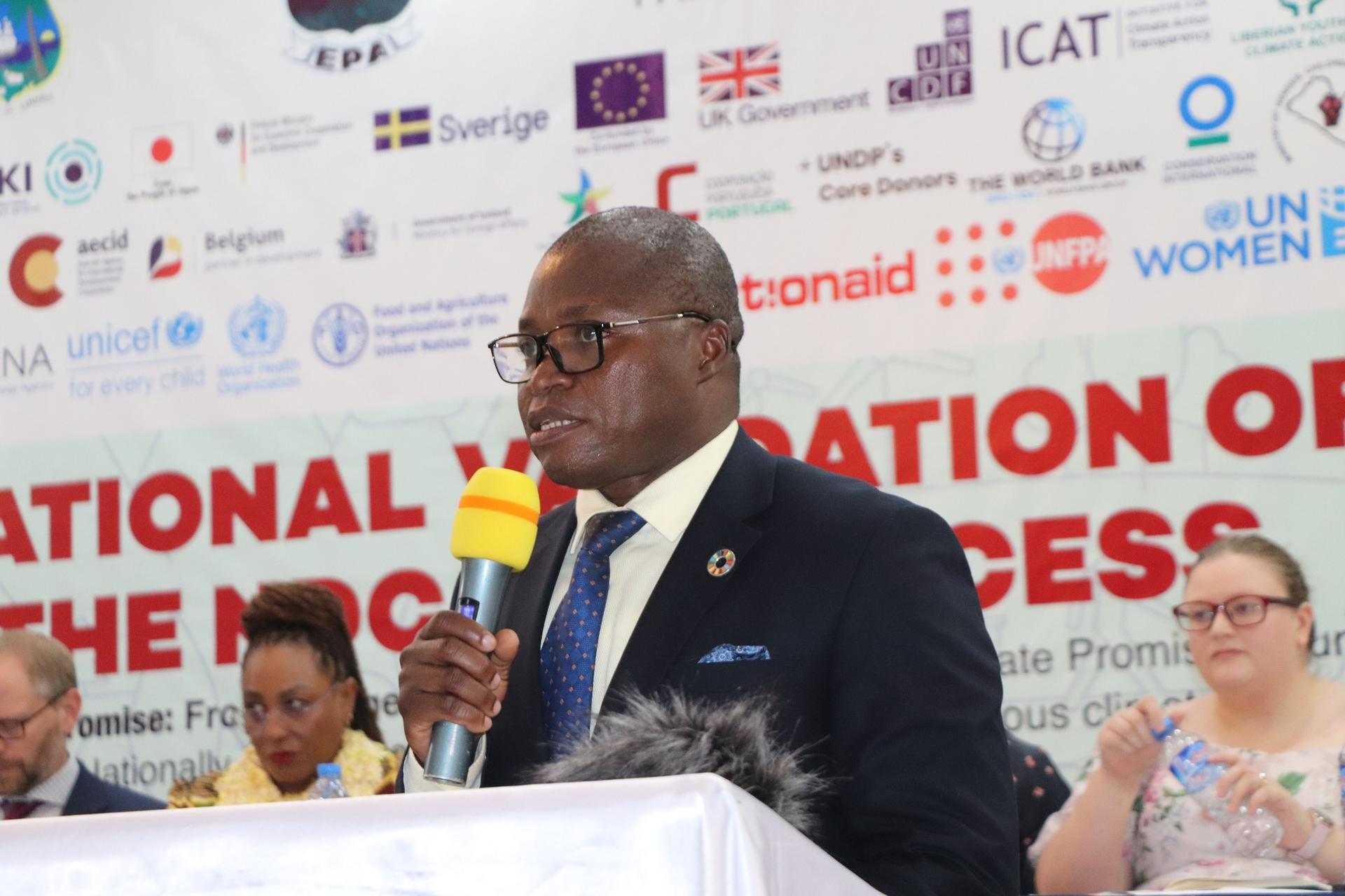 Man in suit at podium speaking into a microphone at an international conference.