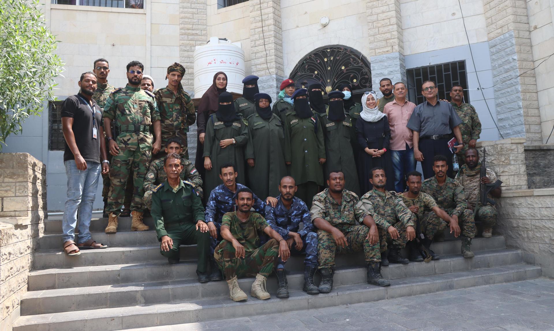 Group of soldiers in uniform posing on stone steps in front of a building.