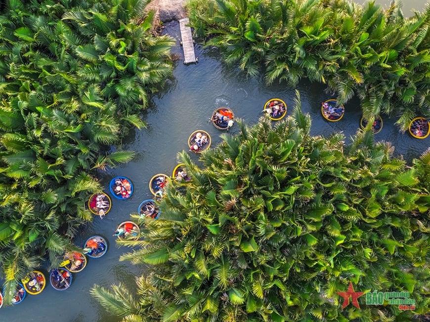 Aerial view of a circular water lagoon edged by palm trees, with many small boats around the edge.