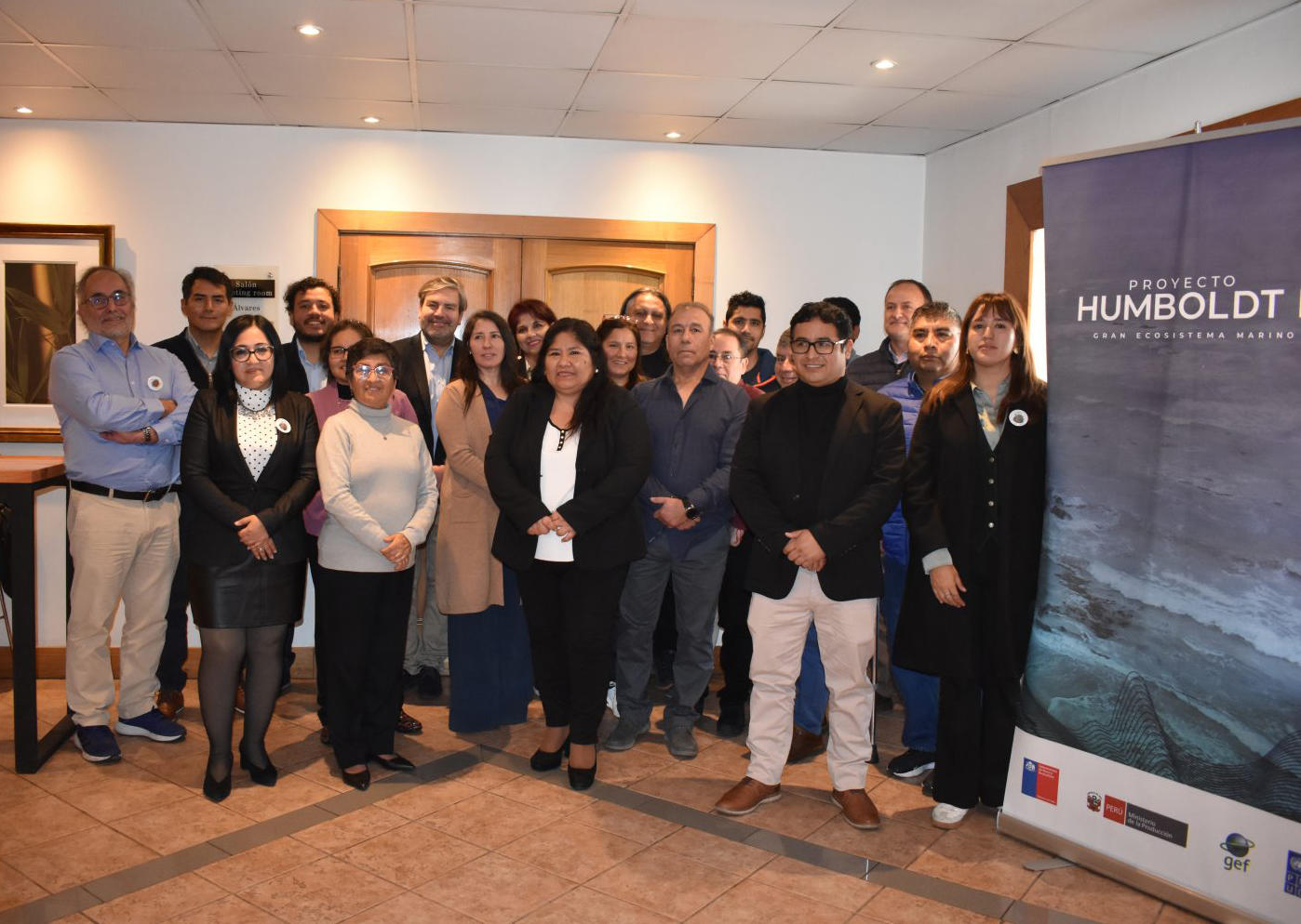 Group of diverse adults posing for a photo at an indoor event, Humboldt banner in the background.