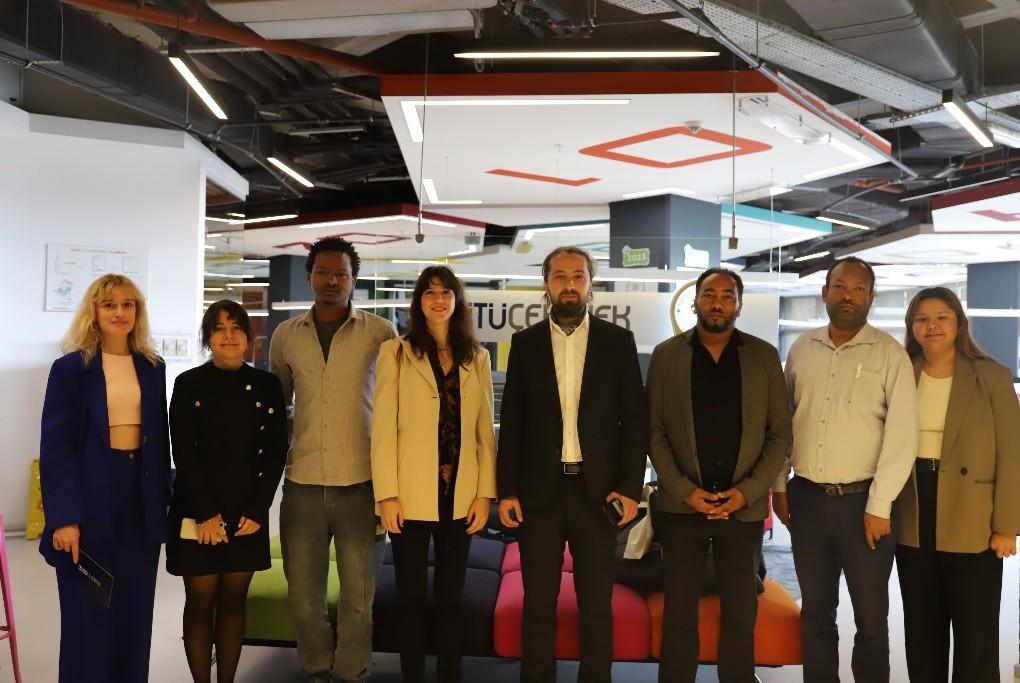 Ten people stand in a bright office lobby, posing for a group photo.