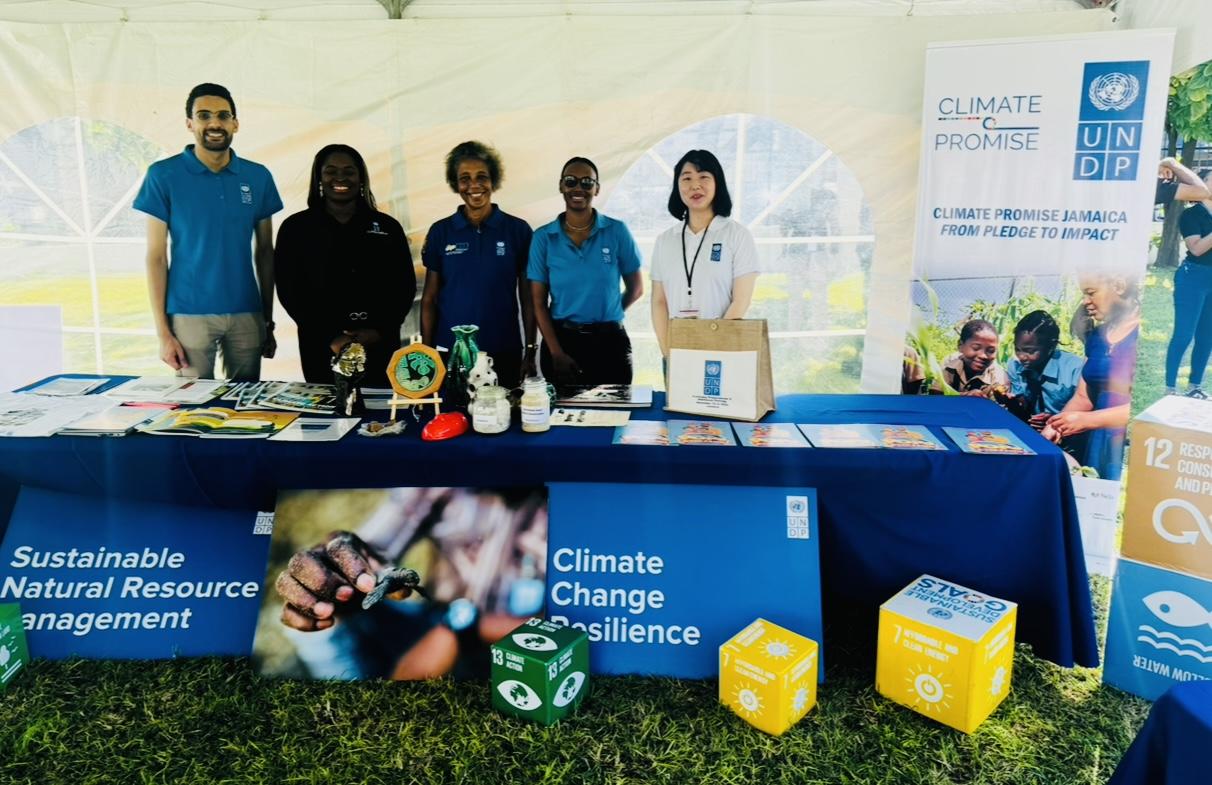 Group of people in blue shirts at an outdoor climate resilience booth with banners.