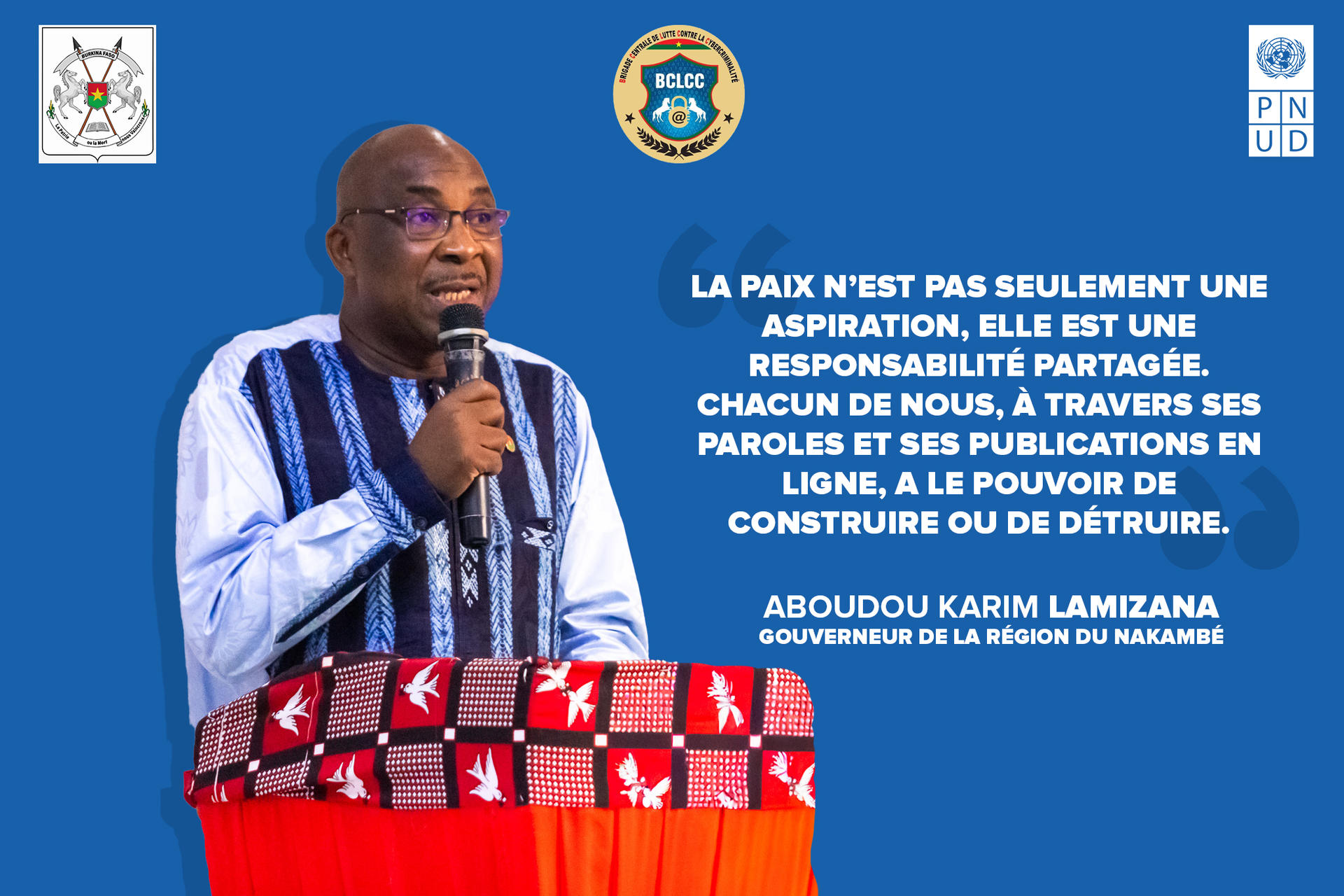 Speaker at a podium on a blue backdrop with official logos.