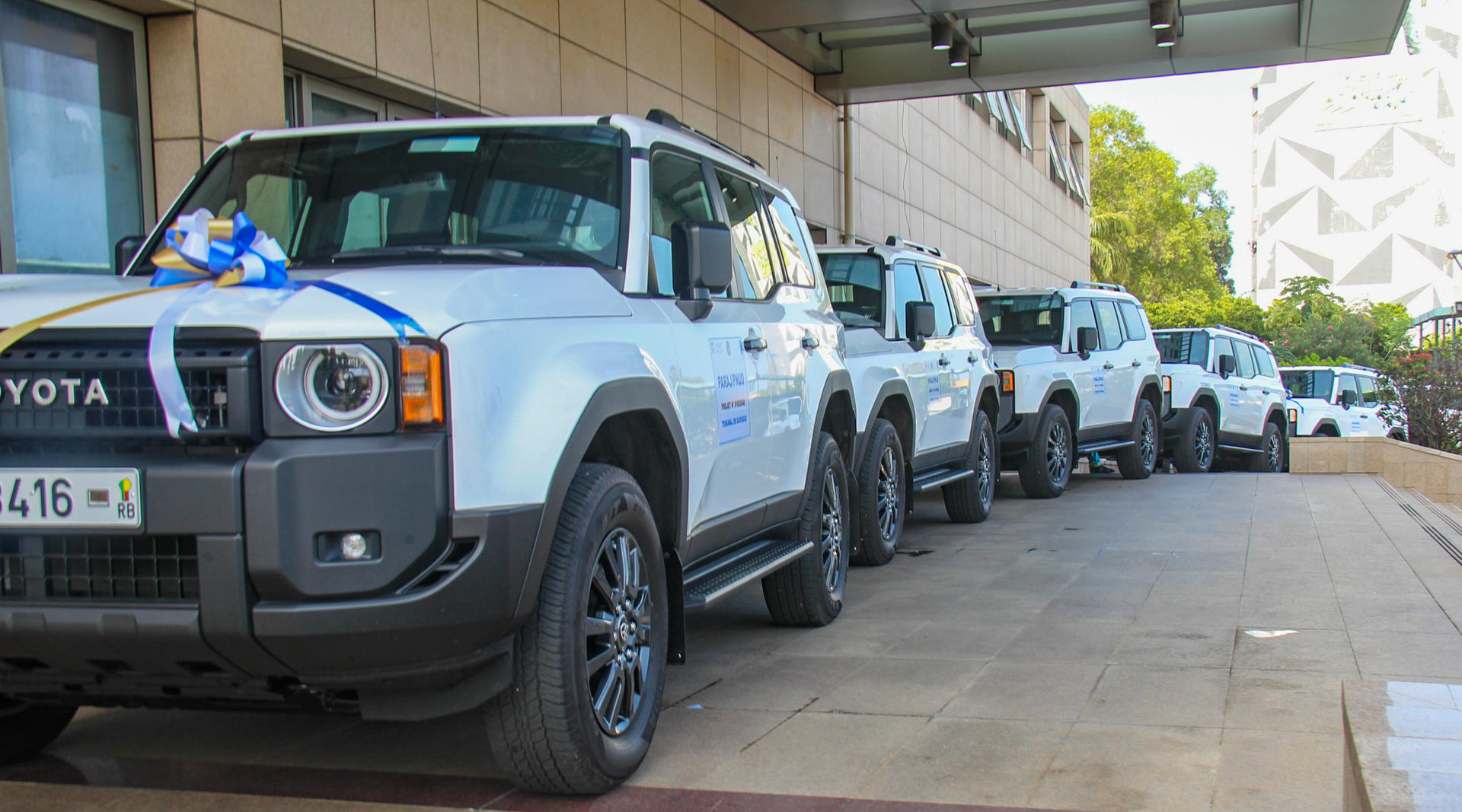 Row of blue Toyota 4x4 SUVs lined up under a covered driveway.