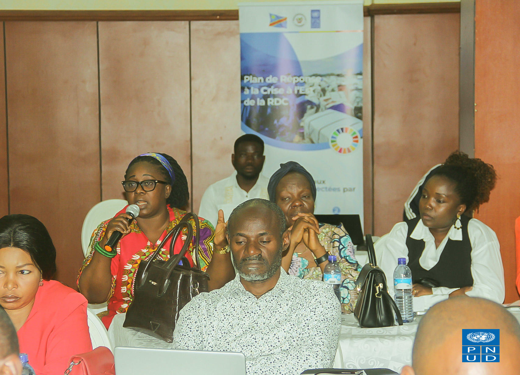 Group photo of diverse attendees at a training workshop in a conference room, banner in back.