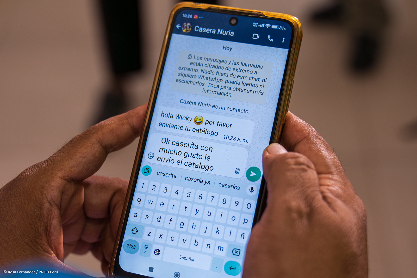 Photograph of two hands holding a blue smartphone displaying a chat conversation.