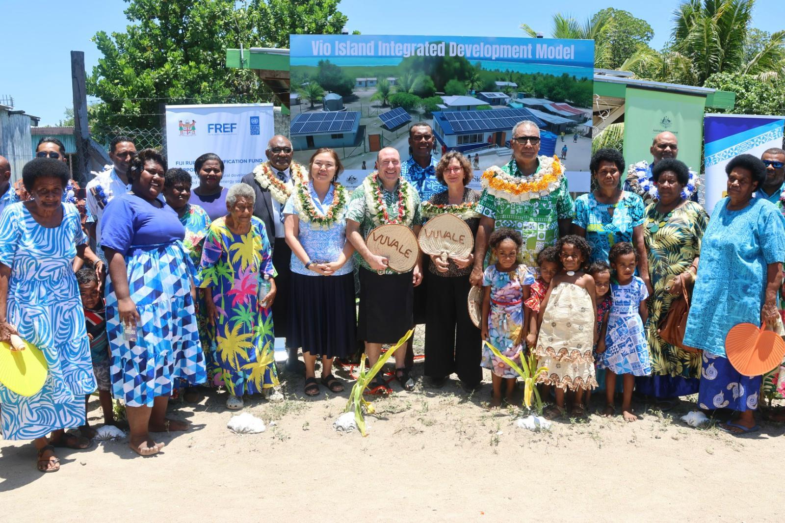 Group of people posing outdoors at a community event with banners behind.