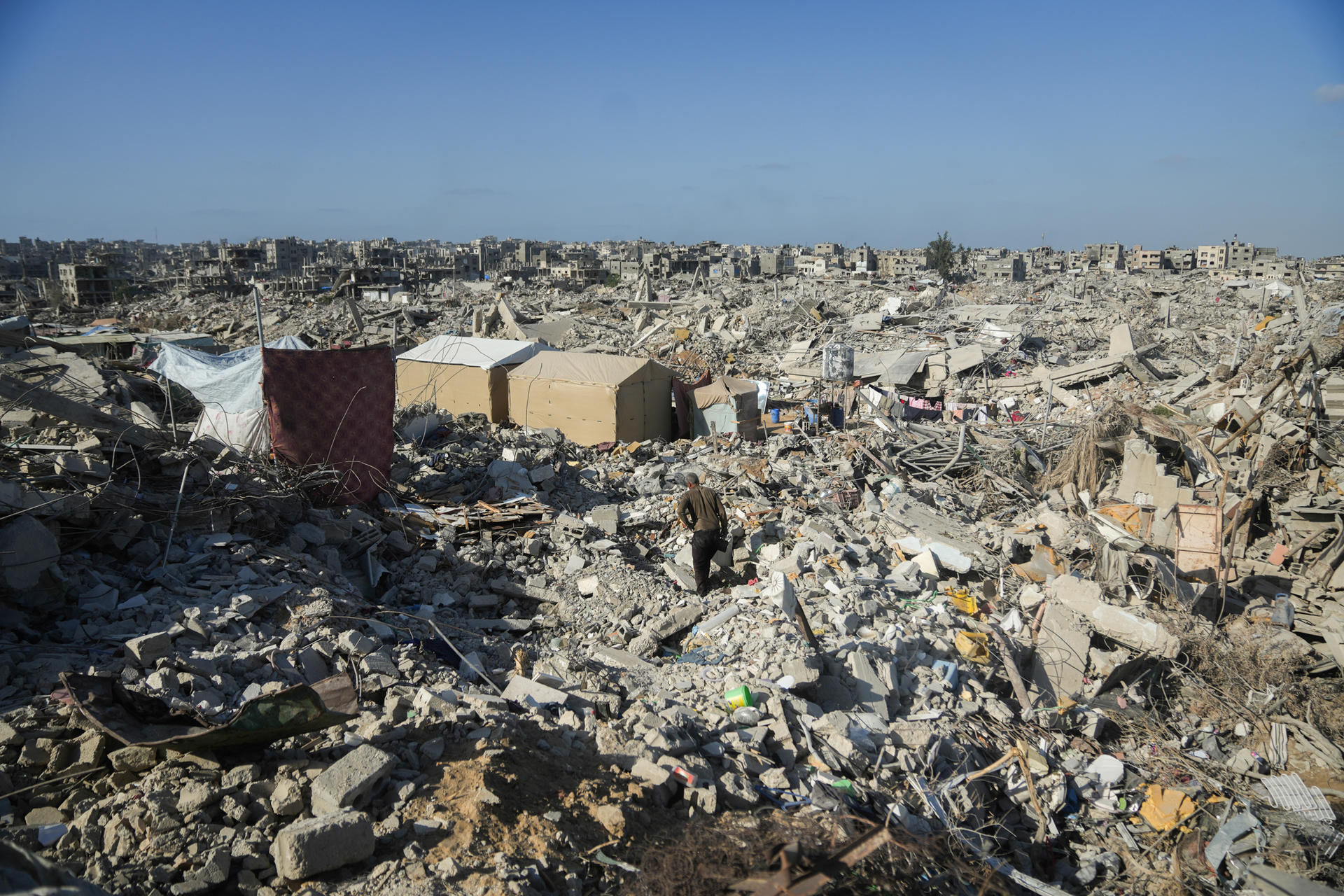 Photograph of a junkyard strewn with rubble and debris under a clear blue sky.