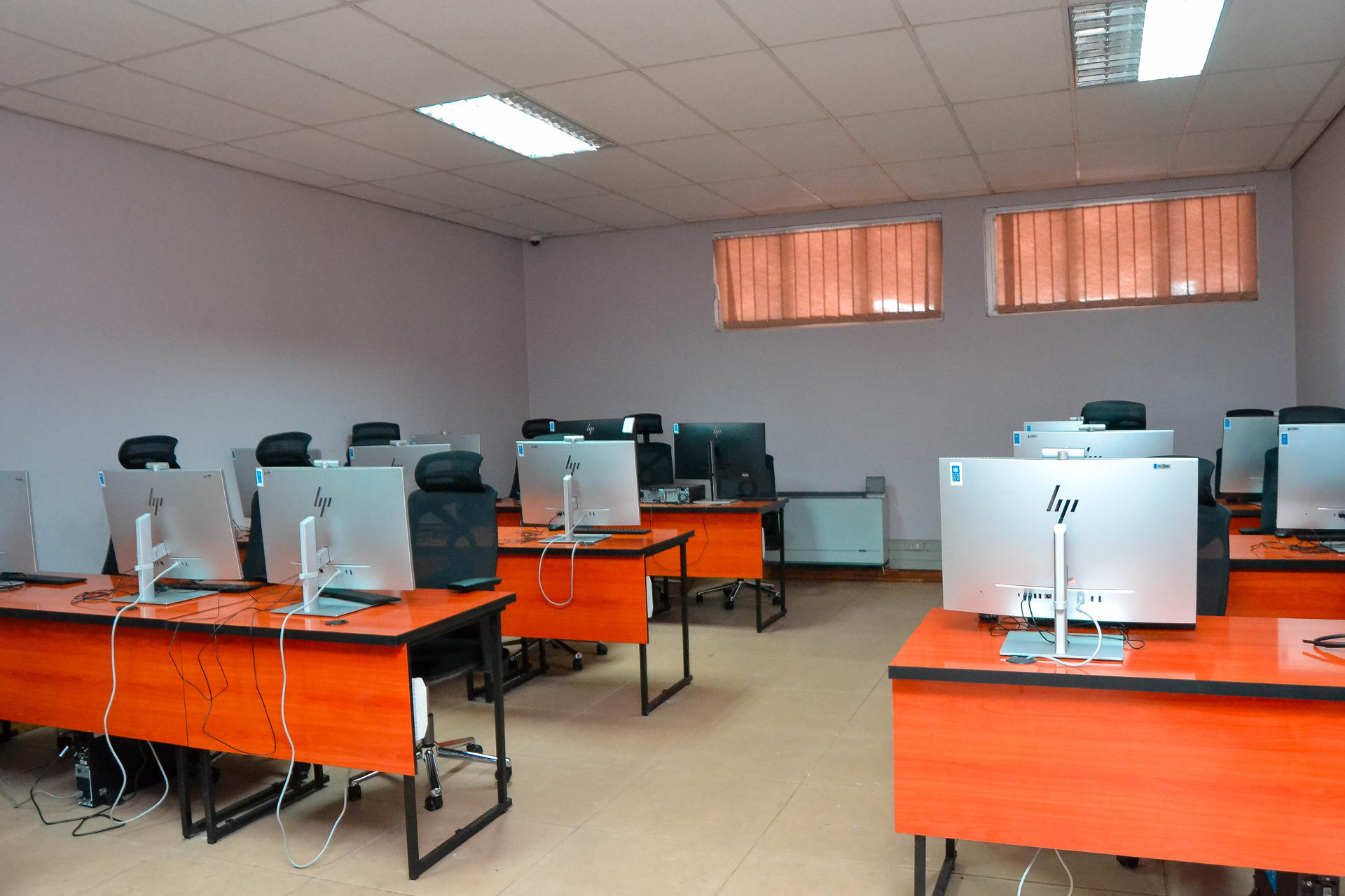 Photograph of a computer lab with rows of orange desks and desktop PCs.