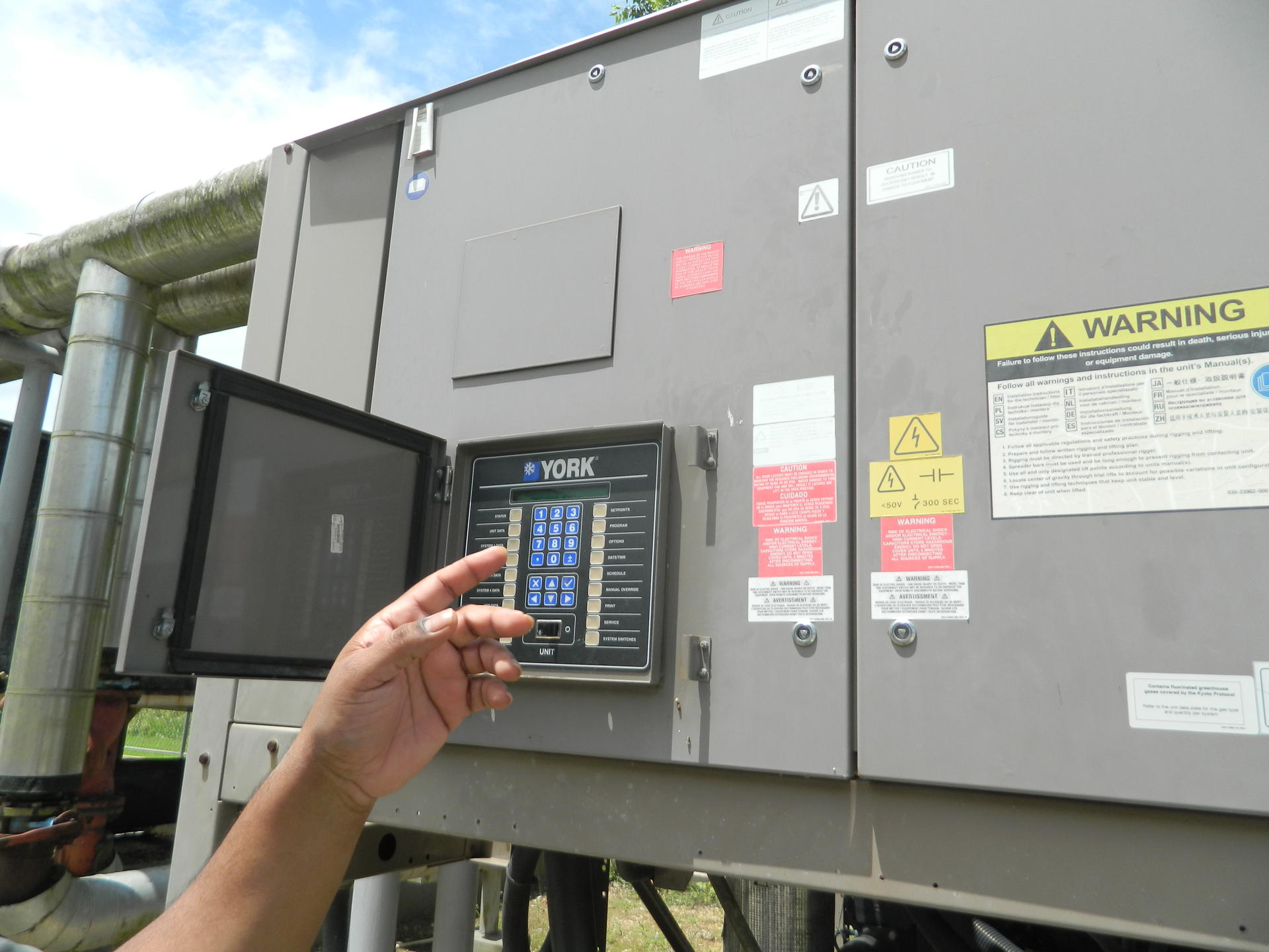 Outdoor electrical control cabinet with a hand pressing a keypad on the panel.