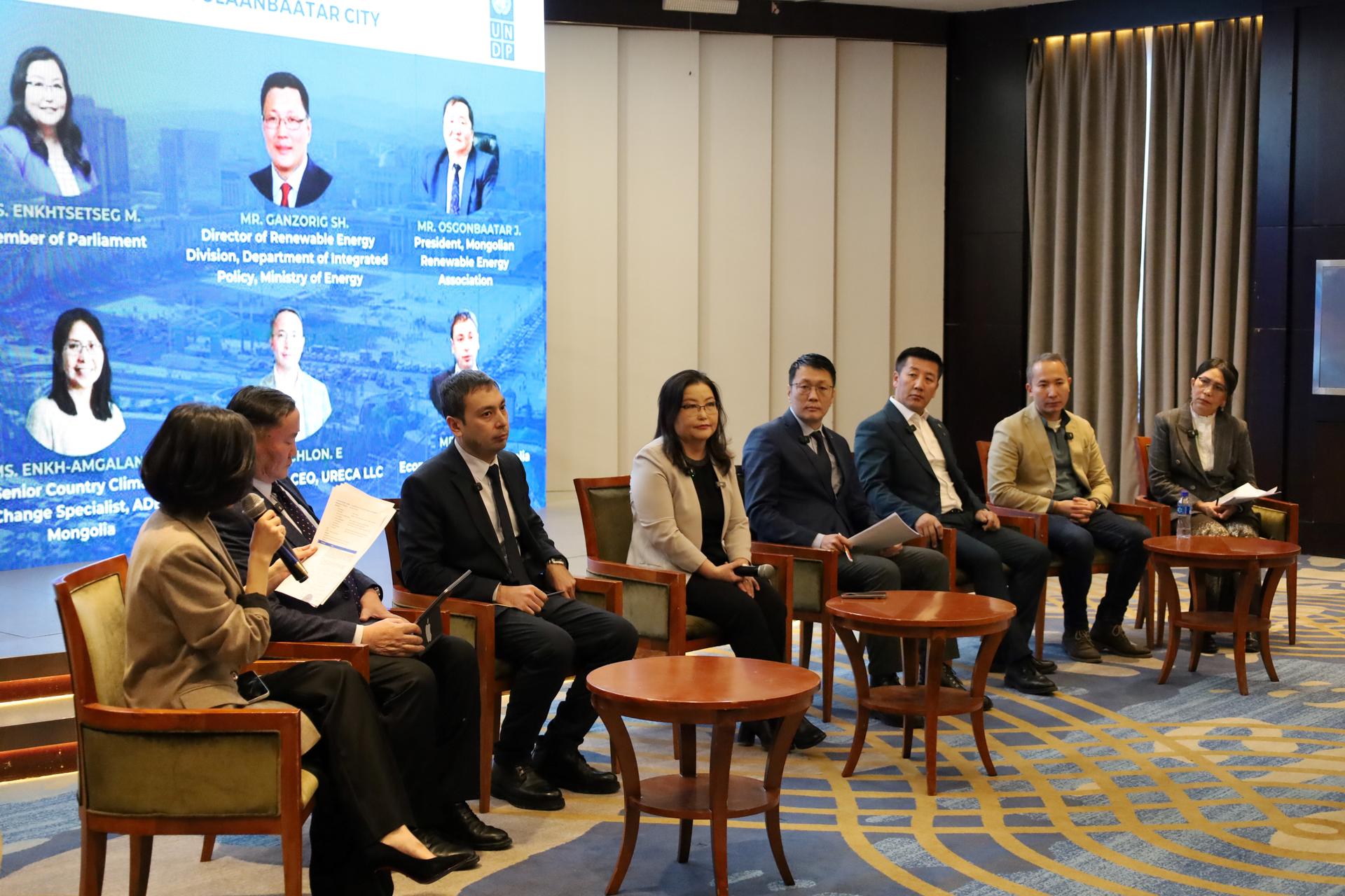 Panelists seated on stage in a conference room with a blue backdrop.