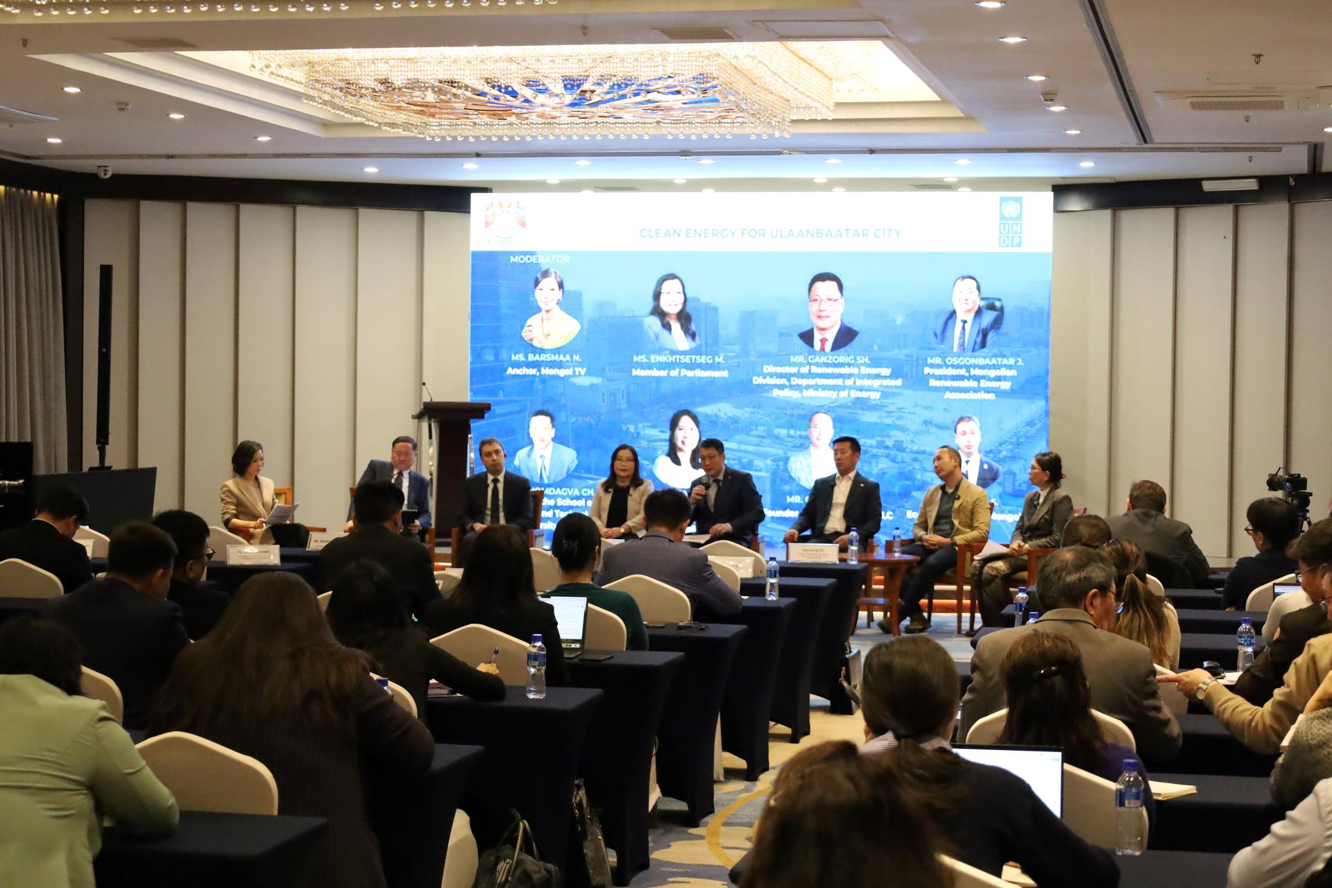 Panel discussion on stage in a conference hall, audience seated and listening.