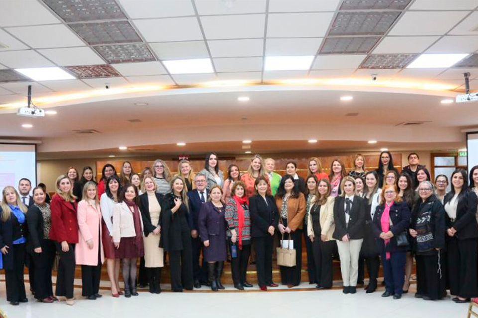 Group photo of a diverse crowd in a conference hall, smiling.