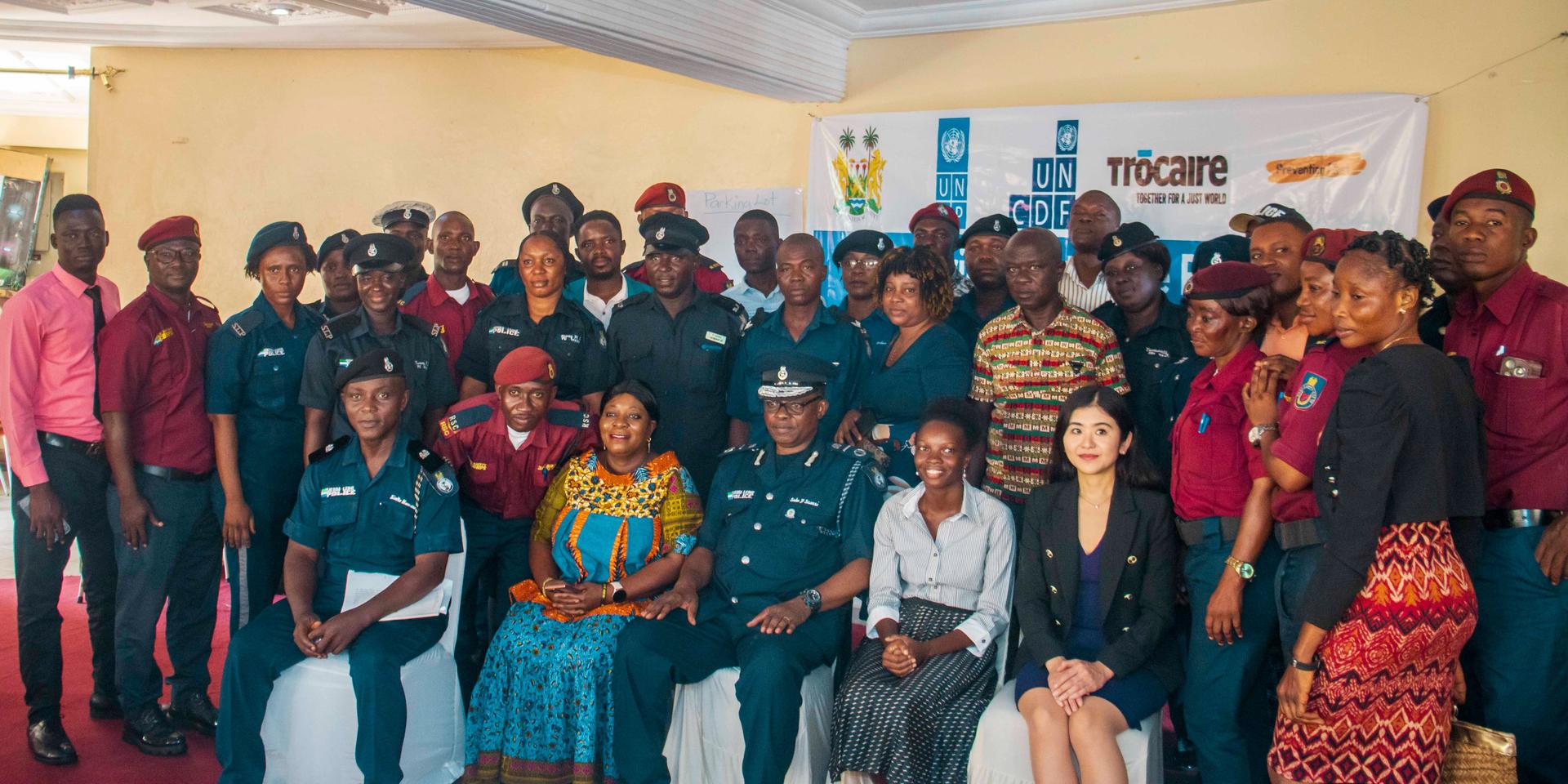 Diverse group of people posing for a photo at an indoor event, banners in the background.