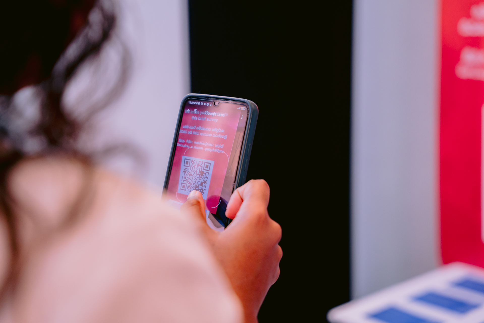 Person from behind holding a smartphone with a messaging app visible on screen.
