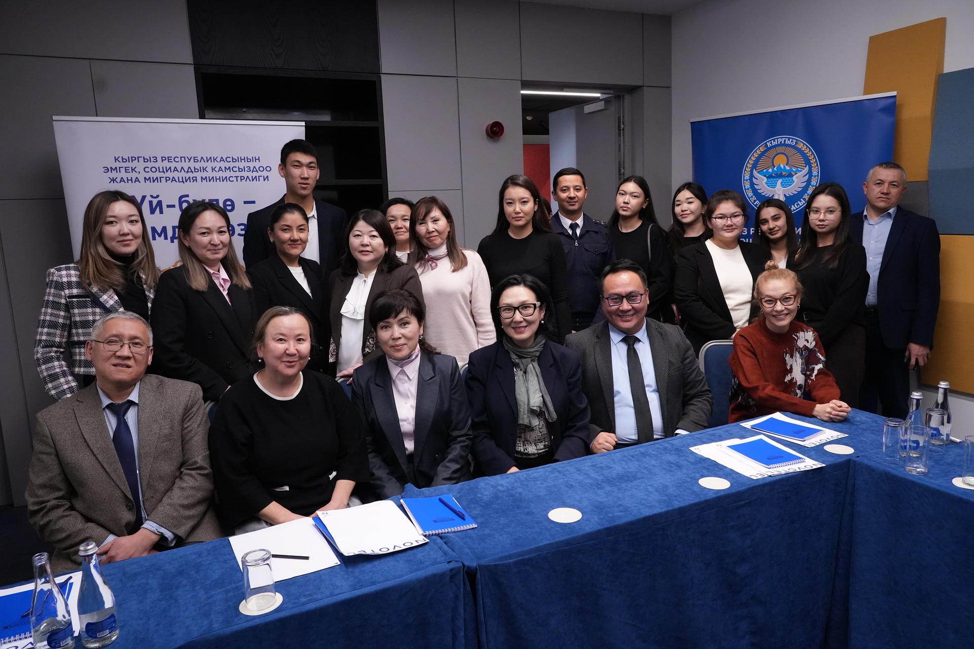 Group of diverse professionals posing for a conference photo around a blue draped table.