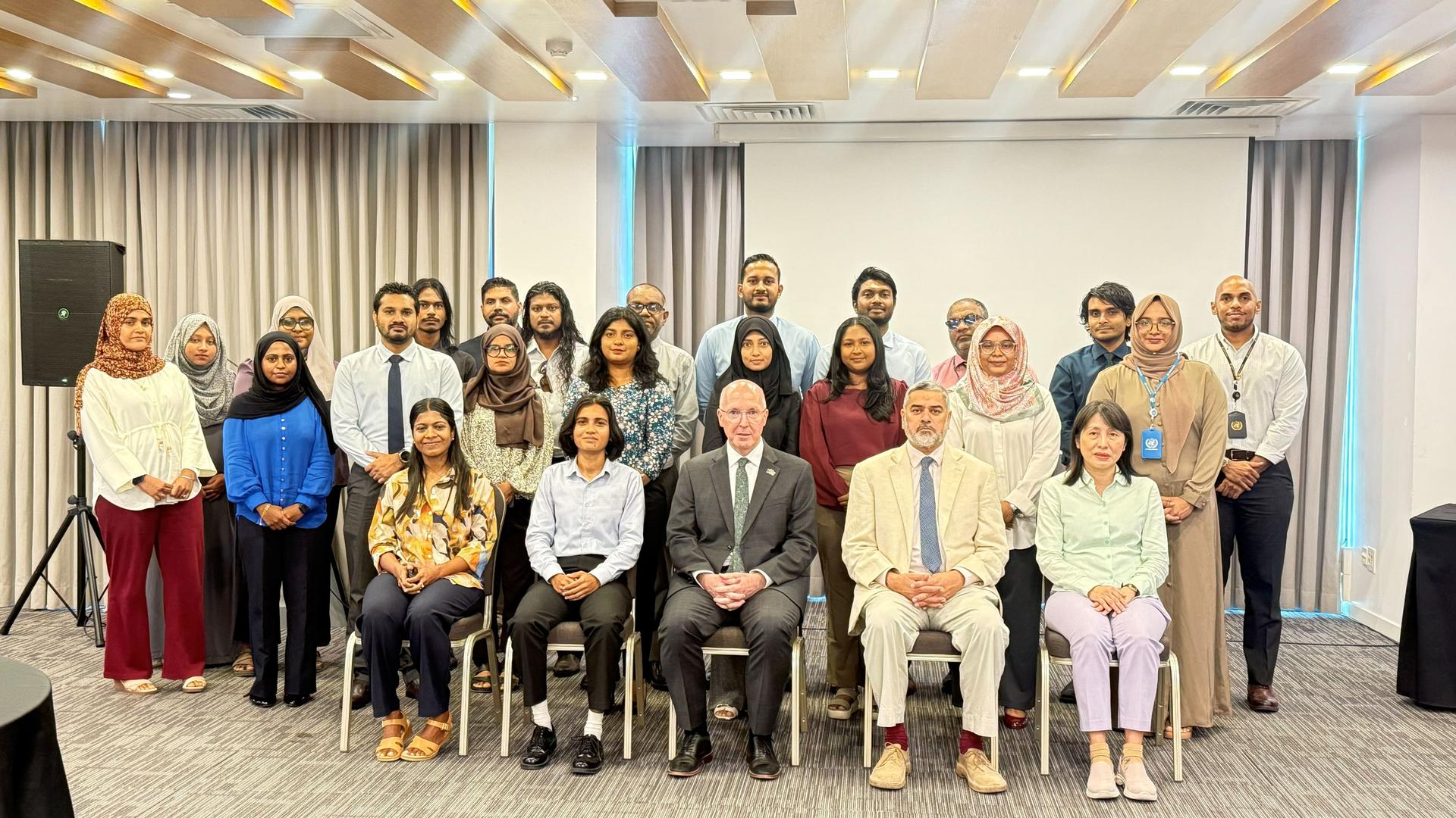Group of adults and children posing and smiling in a conference room.