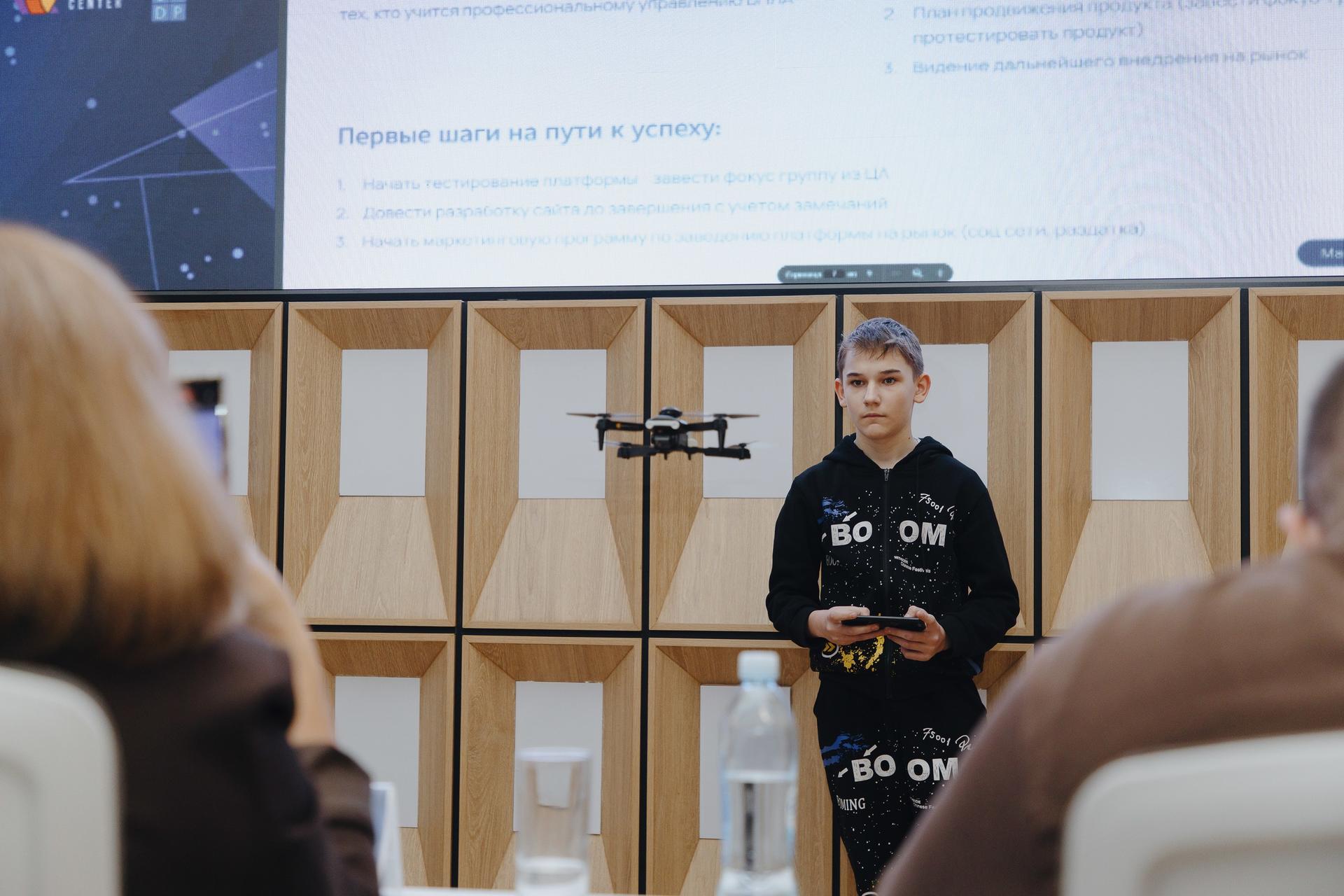 Photograph of a man in a black hoodie giving a talk at a conference, by a microphone stand.