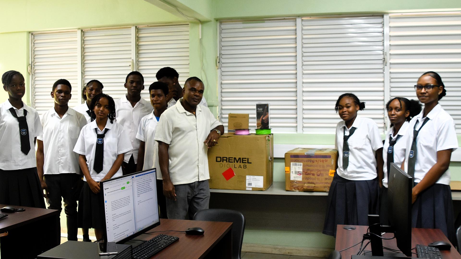 Group of students in white shirts and ties posing in a room with a laptop and boxes.