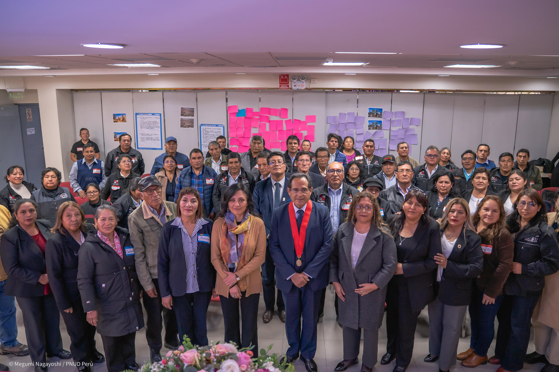 Photograph of a large diverse group at an indoor event posing for a group photo.