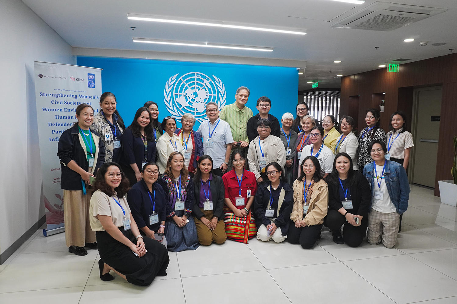 Group photo of diverse professionals posing in front of a UN backdrop at a conference.