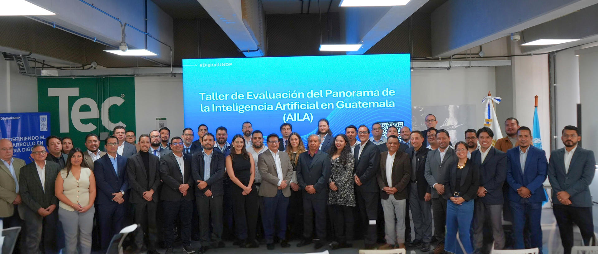 Group of professionals in a conference room posing for a group photo, blue banner in background.
