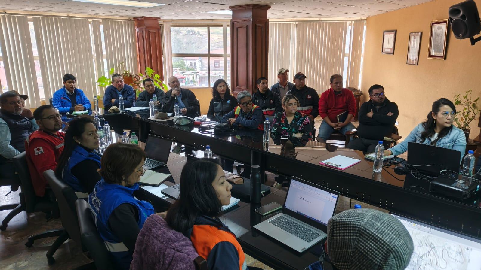 Classroom workshop with a diverse group around a U-shaped table, laptops open.