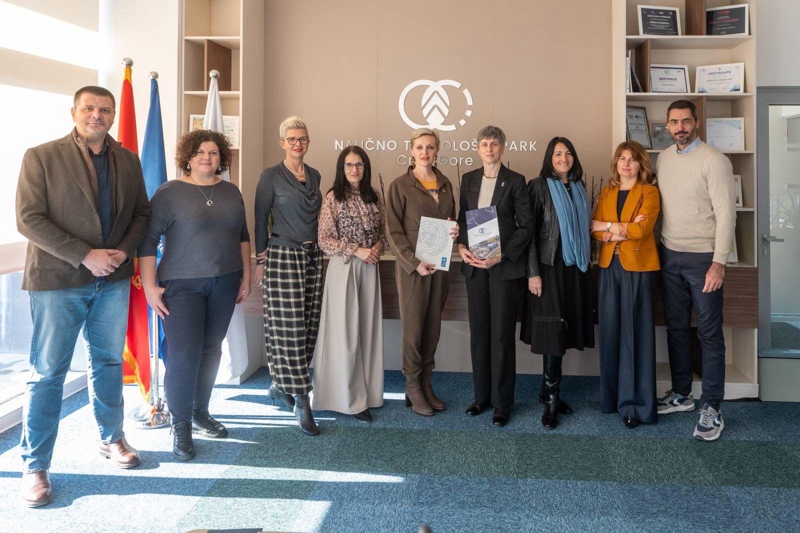 Group of people in a conference room posing with certificates in front of flags and a wall logo.