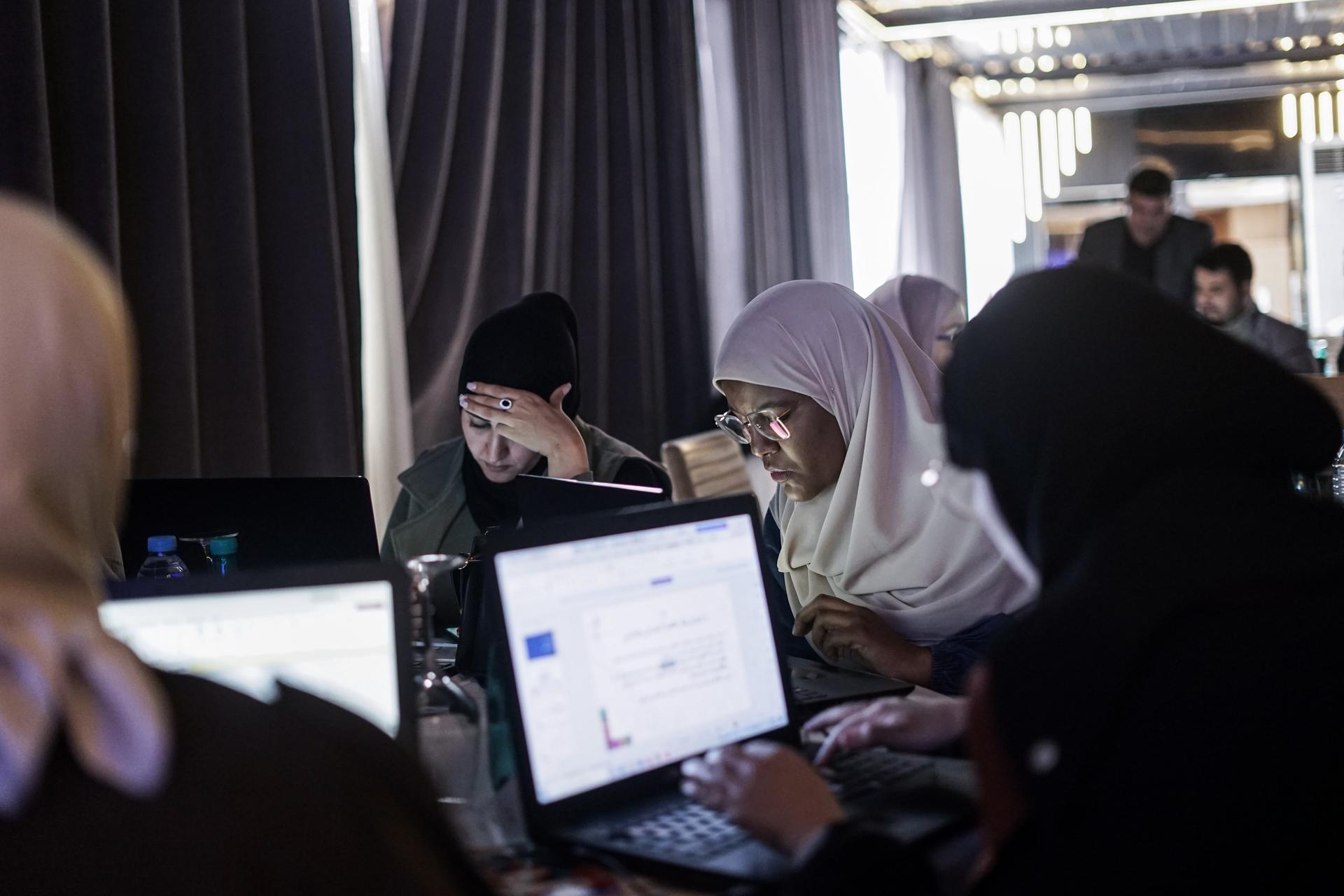 Group of people wearing hijabs using laptops at a computer workshop.