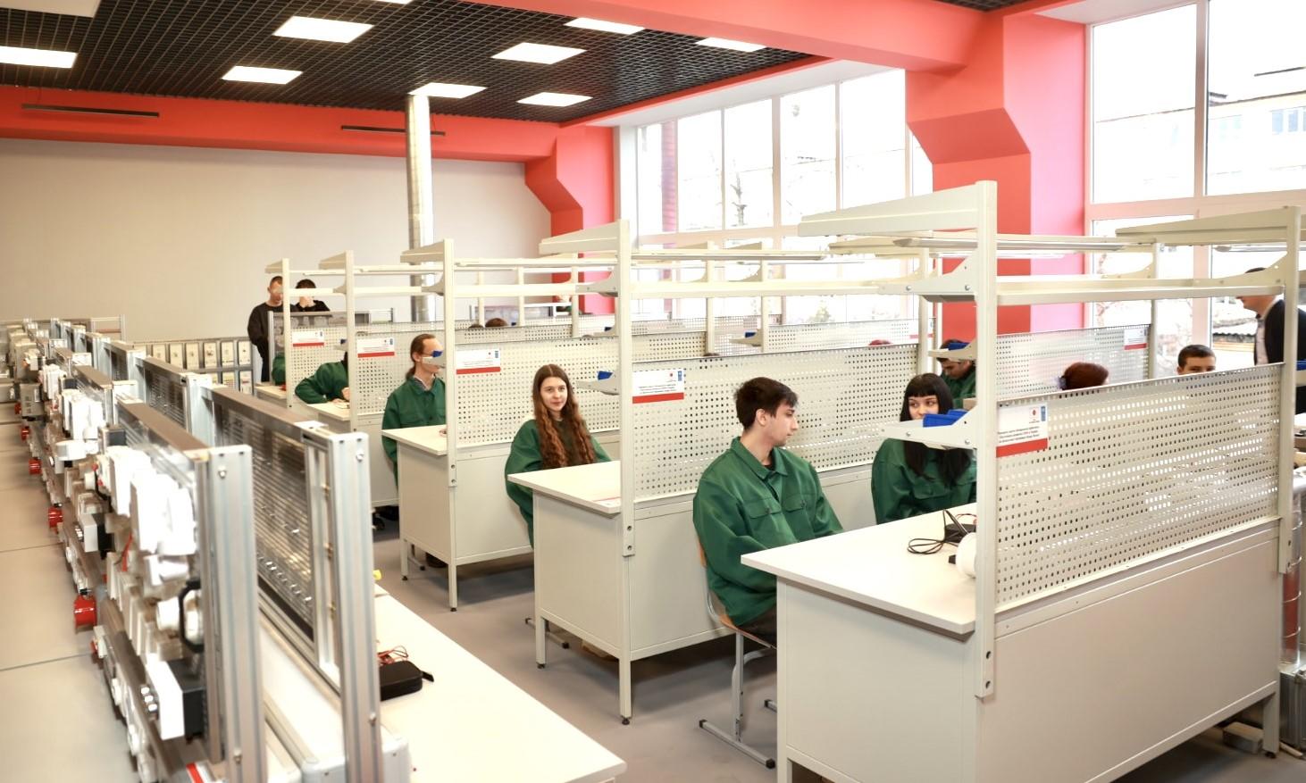 Open-plan office with rows of cubicles and employees at desks; bright lighting and pink columns.