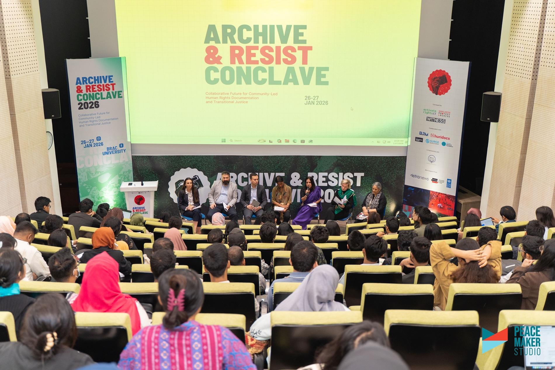Audience seated in a conference hall watching a panel on stage at Archive & Resist Conclave.