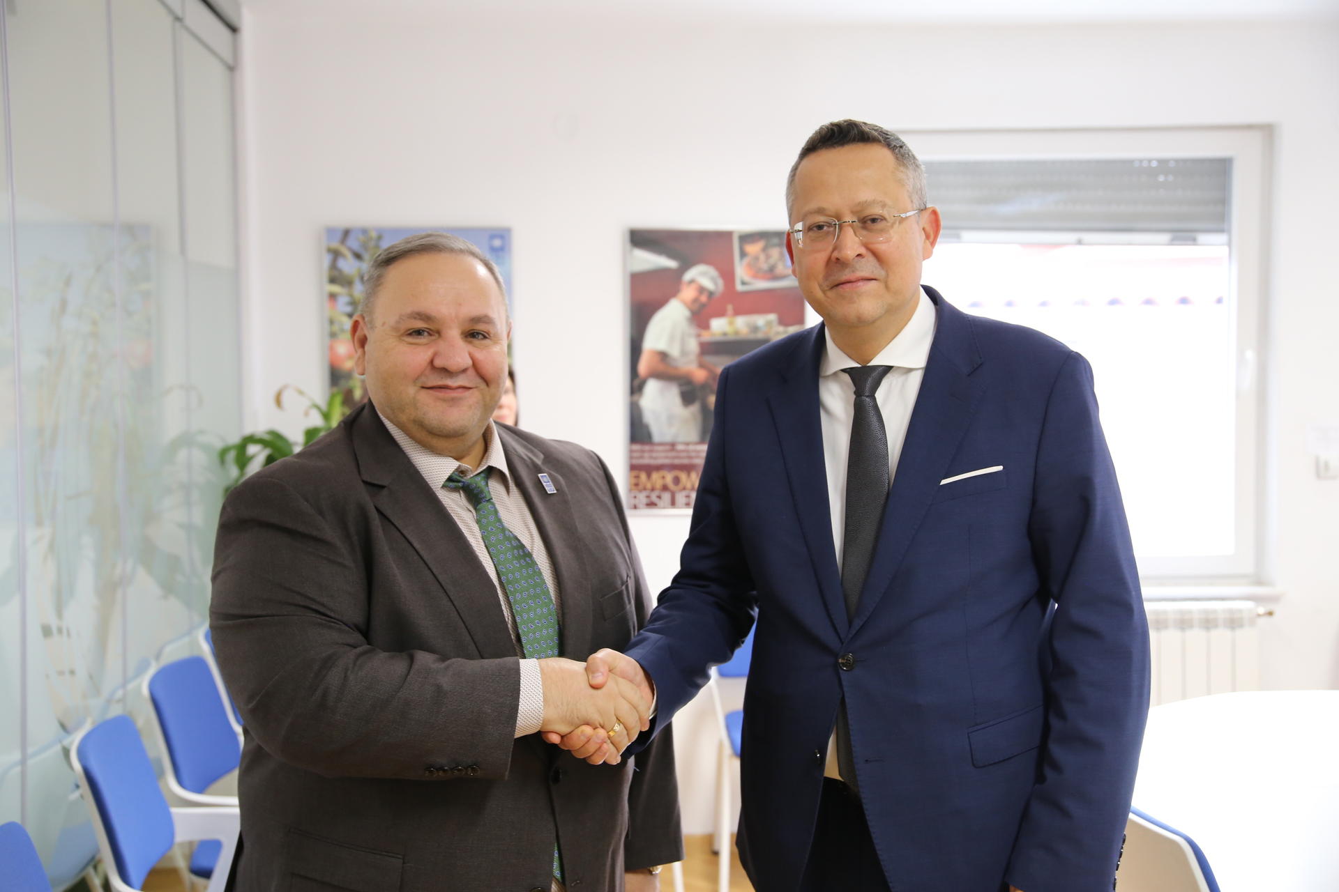 Photograph of two businessmen in suits shaking hands in an office.