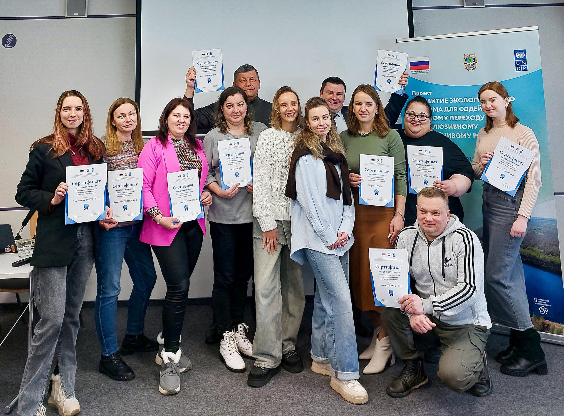 Group of diverse students posing with certificates in a classroom.