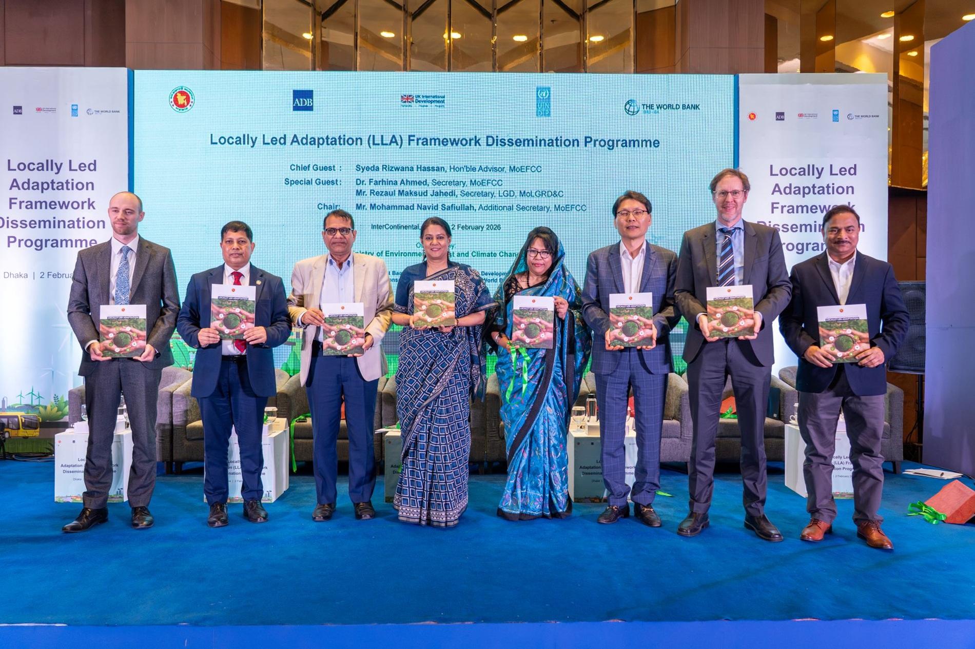 Group of award recipients on stage holding certificates, in formal attire, against a blue backdrop.