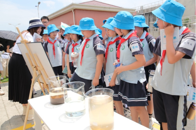 Photo of scouts in blue helmets and red scarves around a table with jars and a pot outdoors.