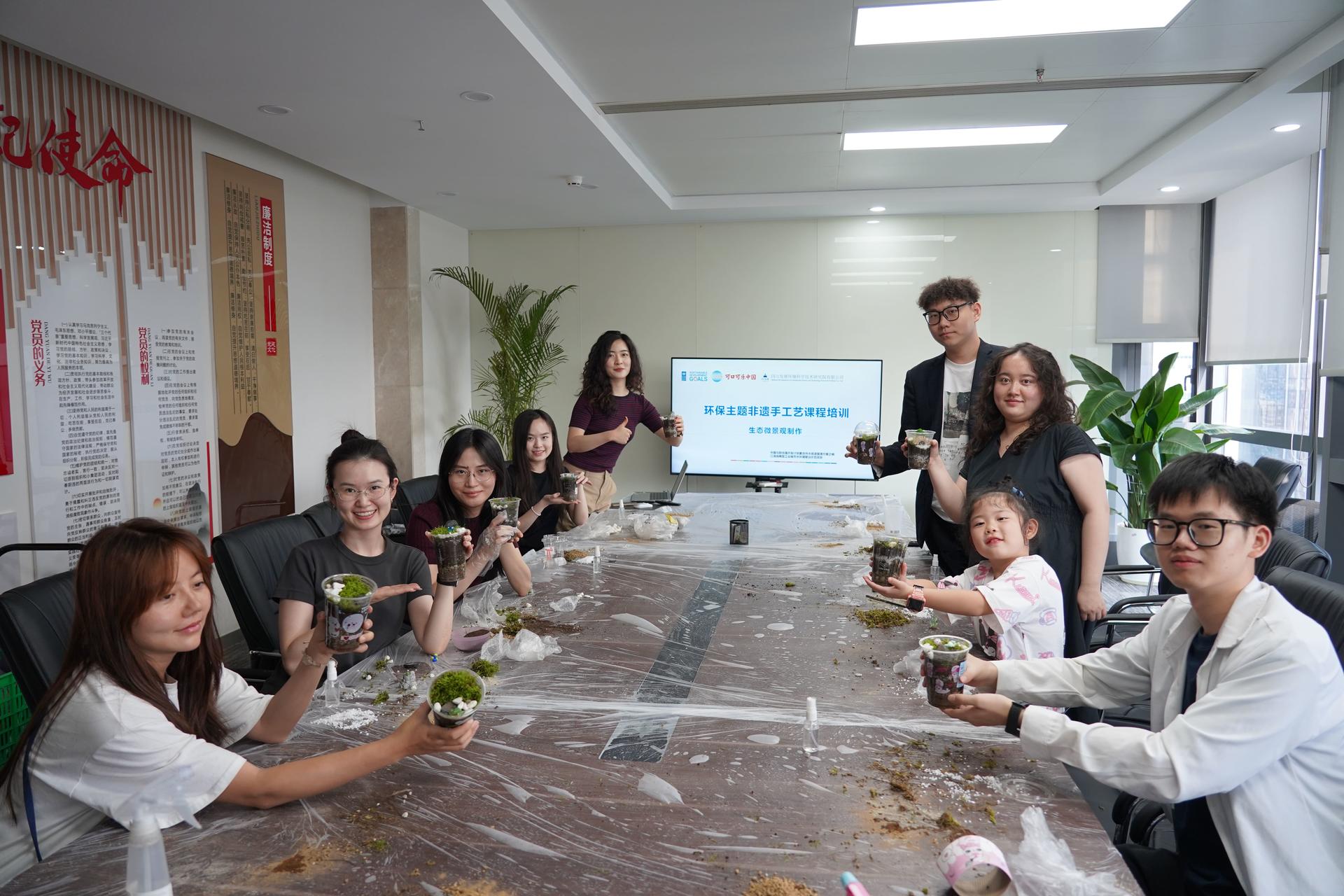 Group of coworkers around a long conference table in a bright office, smiling at the camera.