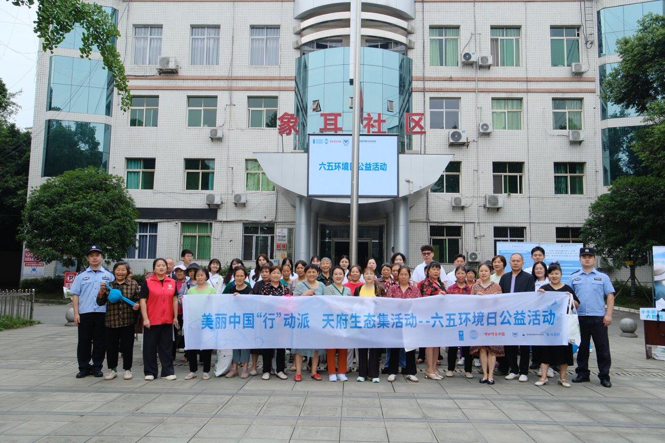 Group of people posing with a banner in front of a campus building.