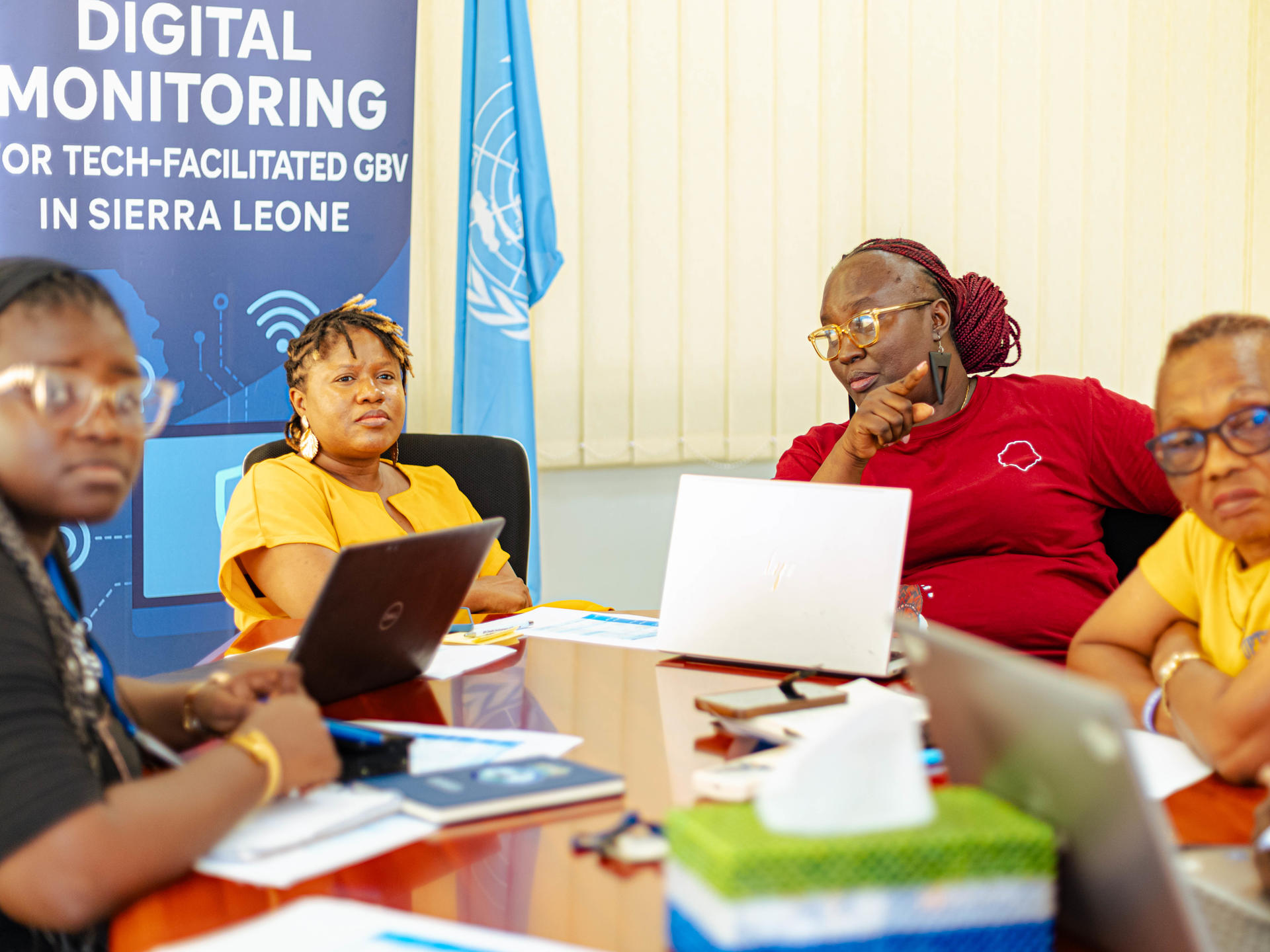 Group of people around a table with laptops; blue Digital Monitoring banner in the background.