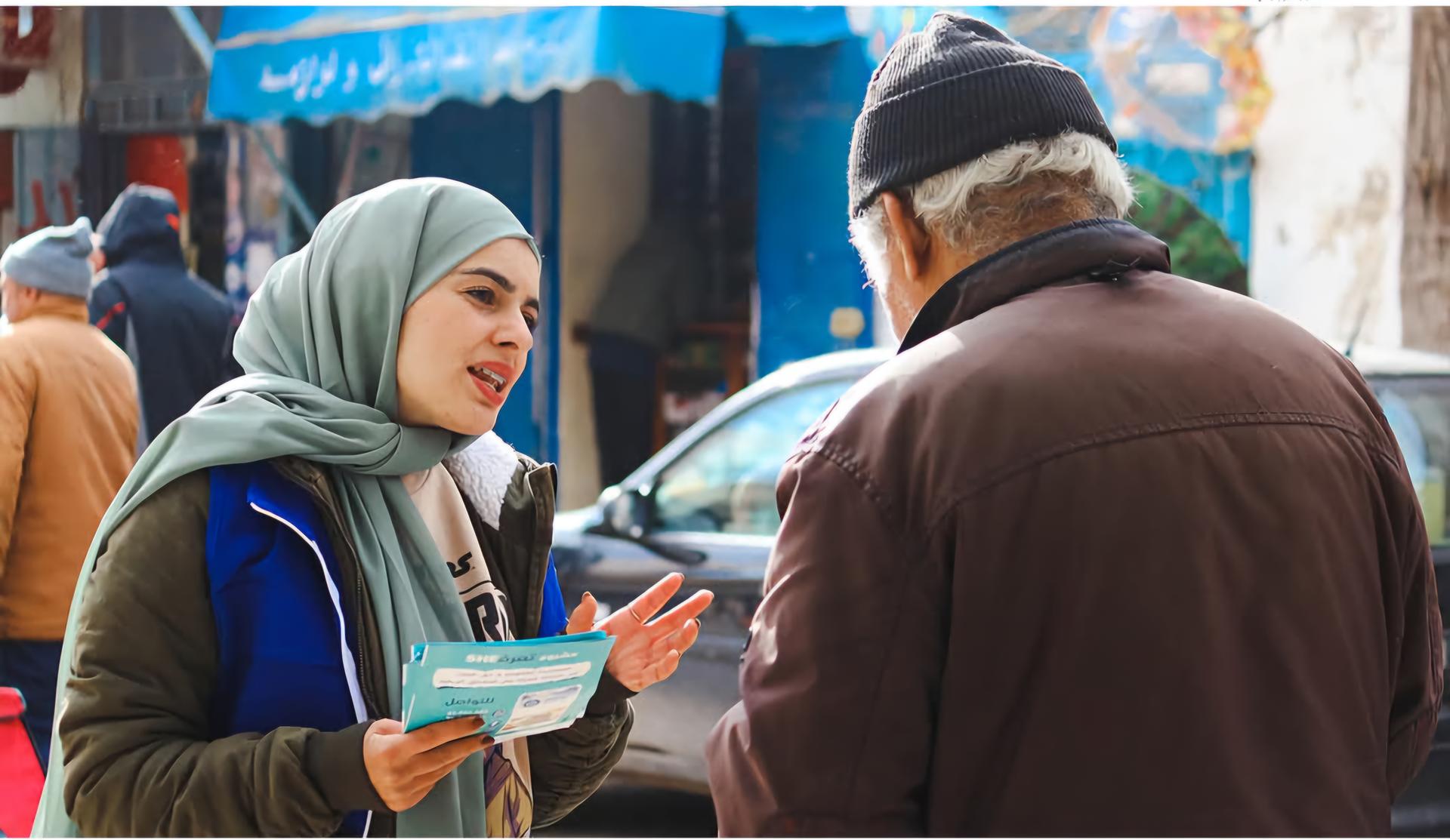 Discussion entre une femme de la société civile et un citoyen, sur l'aide legal lors d'une campagne de sensibilisation
