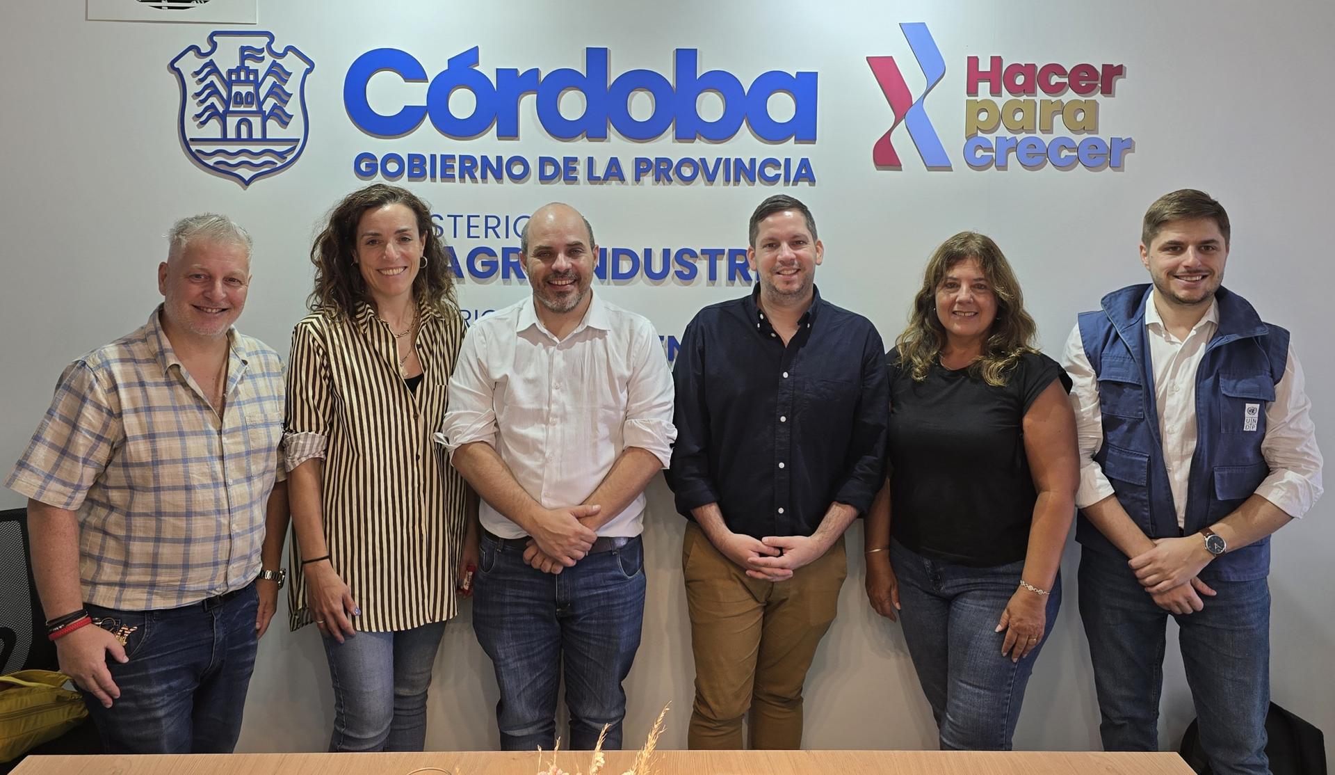 Group of seven people posing in front of Córdoba government logos.