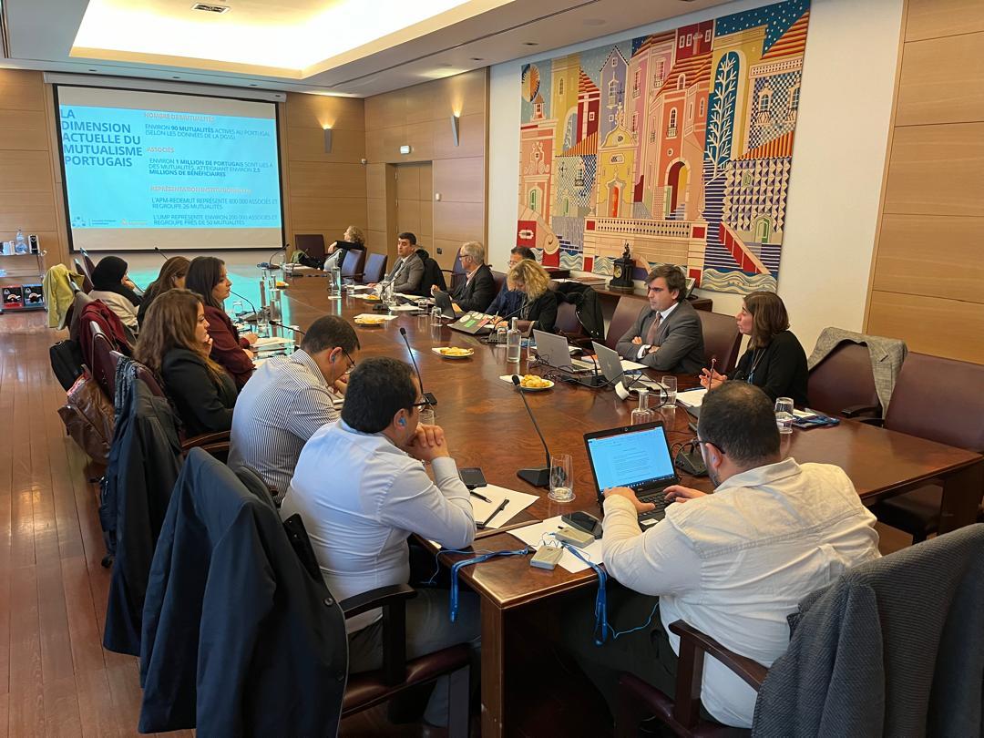 Group of professionals around a long conference table, presentation on screen.
