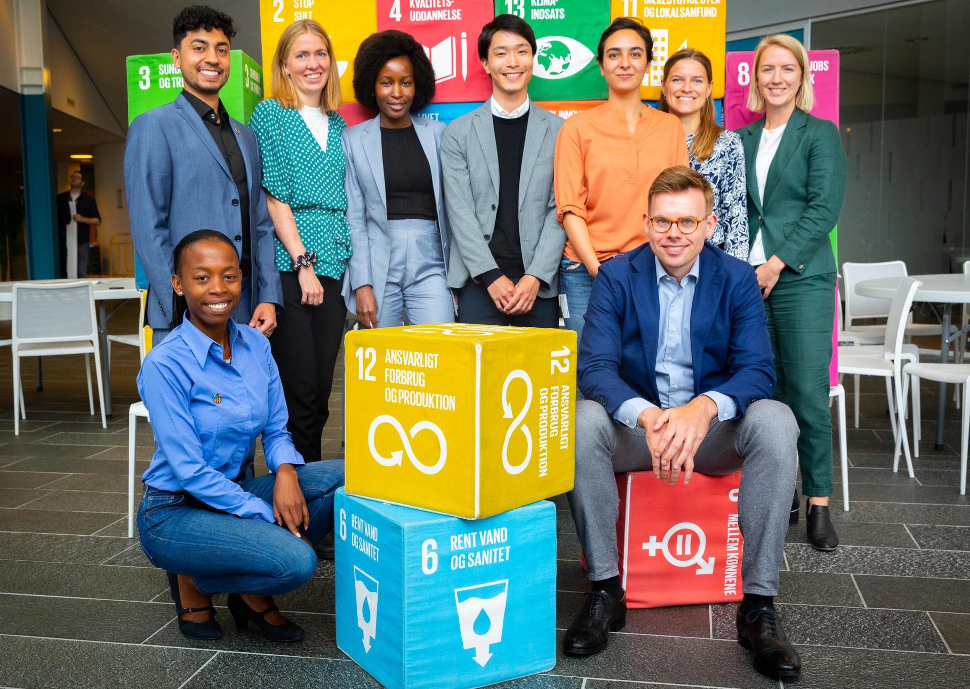 Group of people posing with large yellow and blue Sustainable Development Goals boxes.