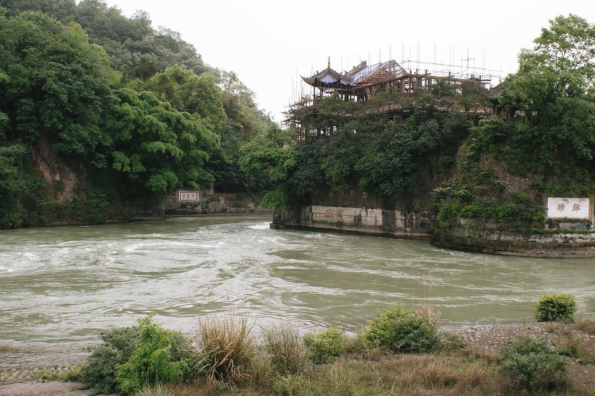 Photograph of a river winding through green hills with a hillside pavilion.