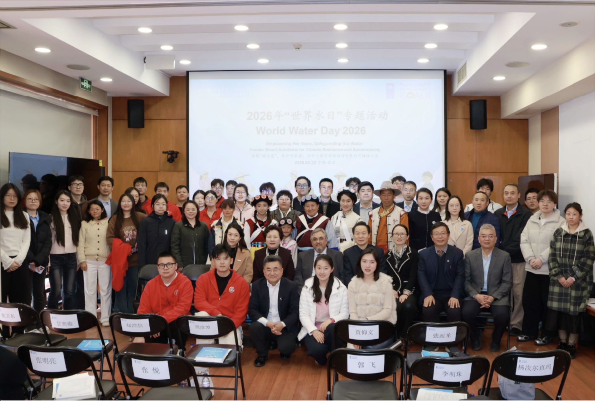 Group photo of a large, diverse group in a conference room with a projector screen behind.