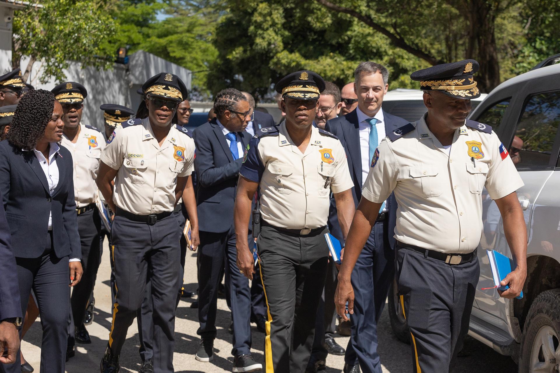 Photograph of uniformed officers and officials walking together down a sunny street.