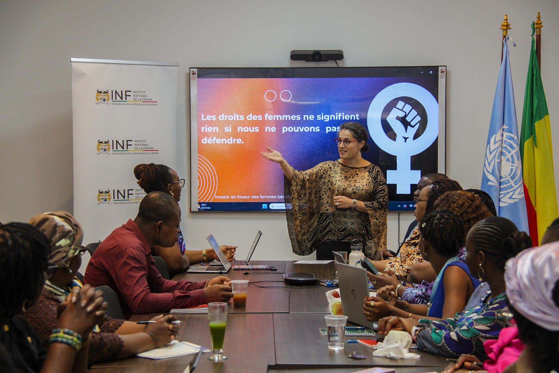 Photo: Diverse group around a conference table as a presenter points to a slide showing a globe.