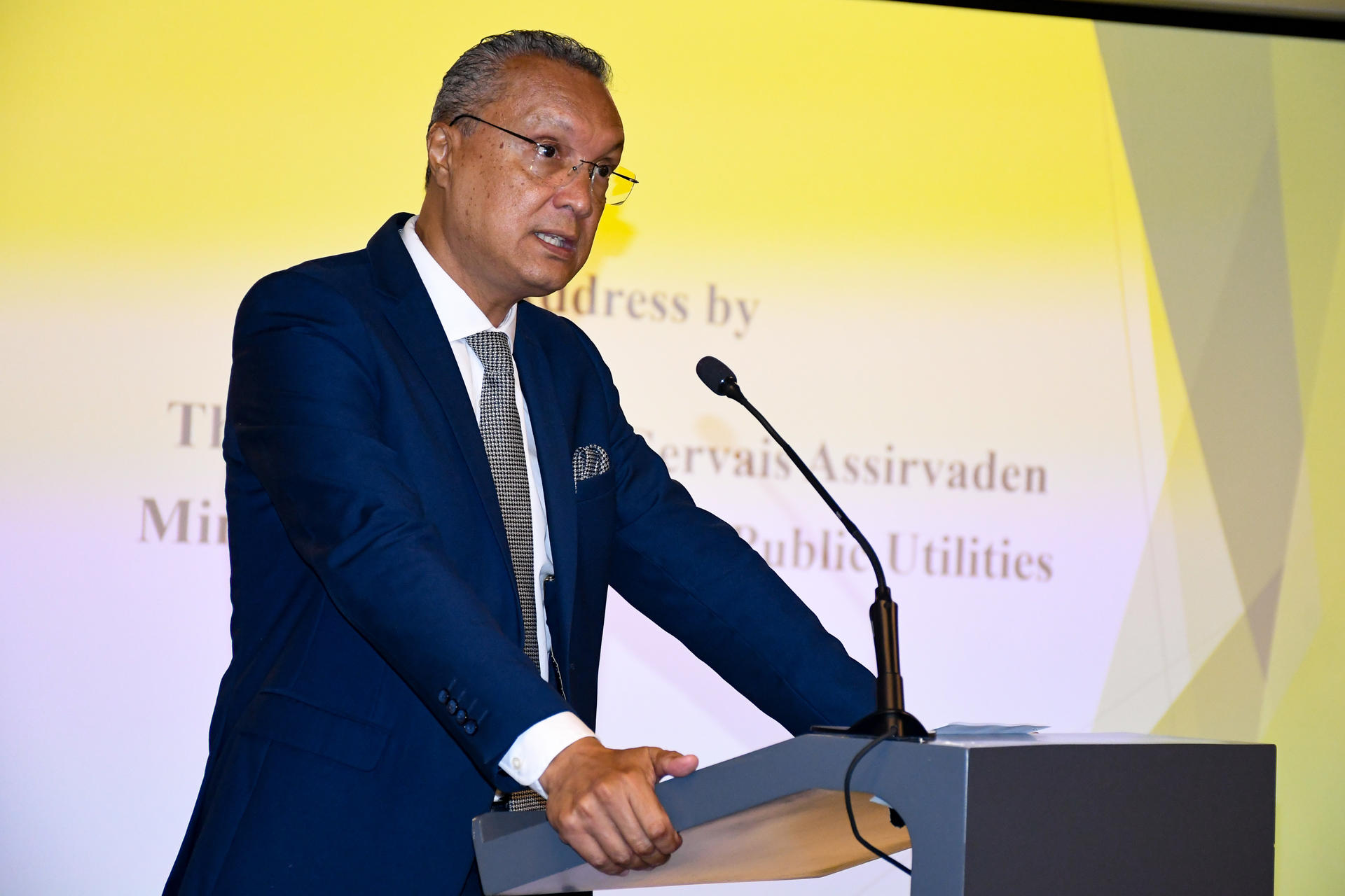 Speaker in a blue suit at a lectern on a stage with a yellow backdrop.undp-mru-gef-6-prodoc-signature-36.jpg