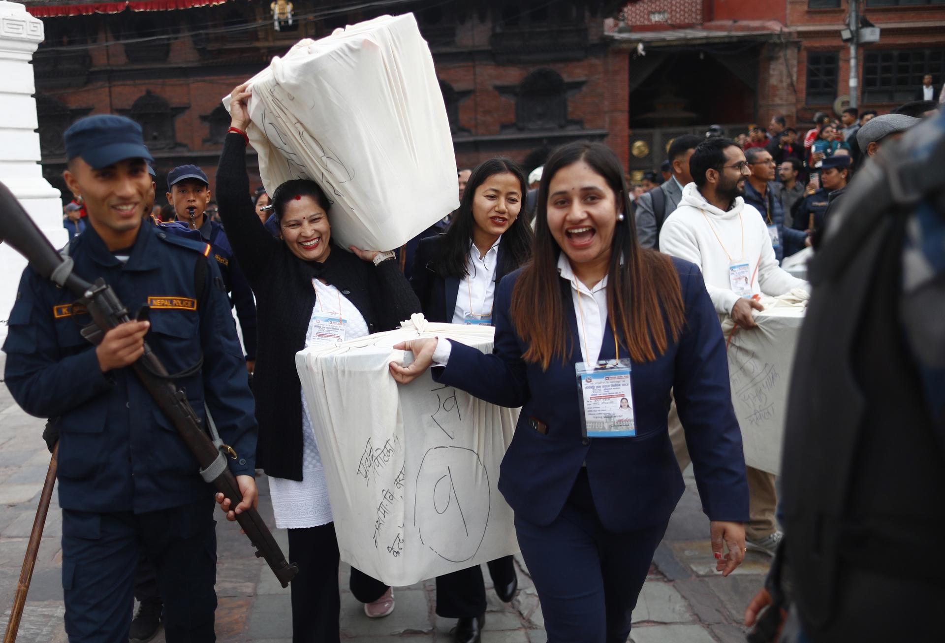 Volunteers in blue vests distribute large white cushions to a crowd in a plaza.